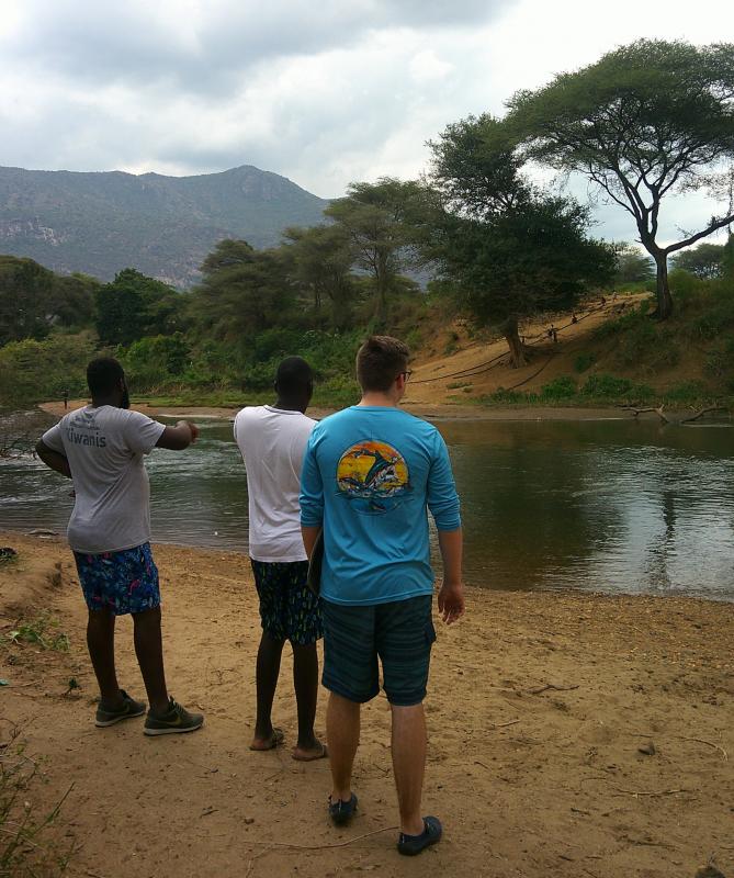 Cape High sophomore Logan Almond, right, with Kenya Gather board members Tom Angote, left, and Meshack Kiprono observe workers on the far hillside involved in gold mining beside the Turkwel River.